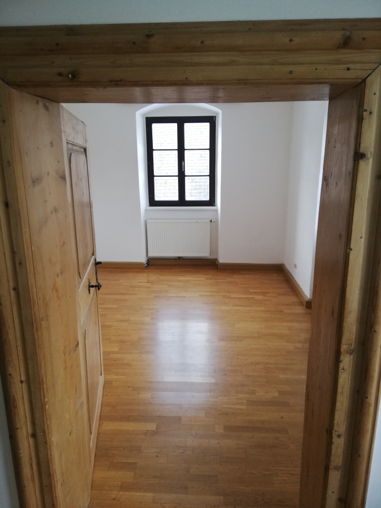 ein Zimmer mit Holzboden und Fenster